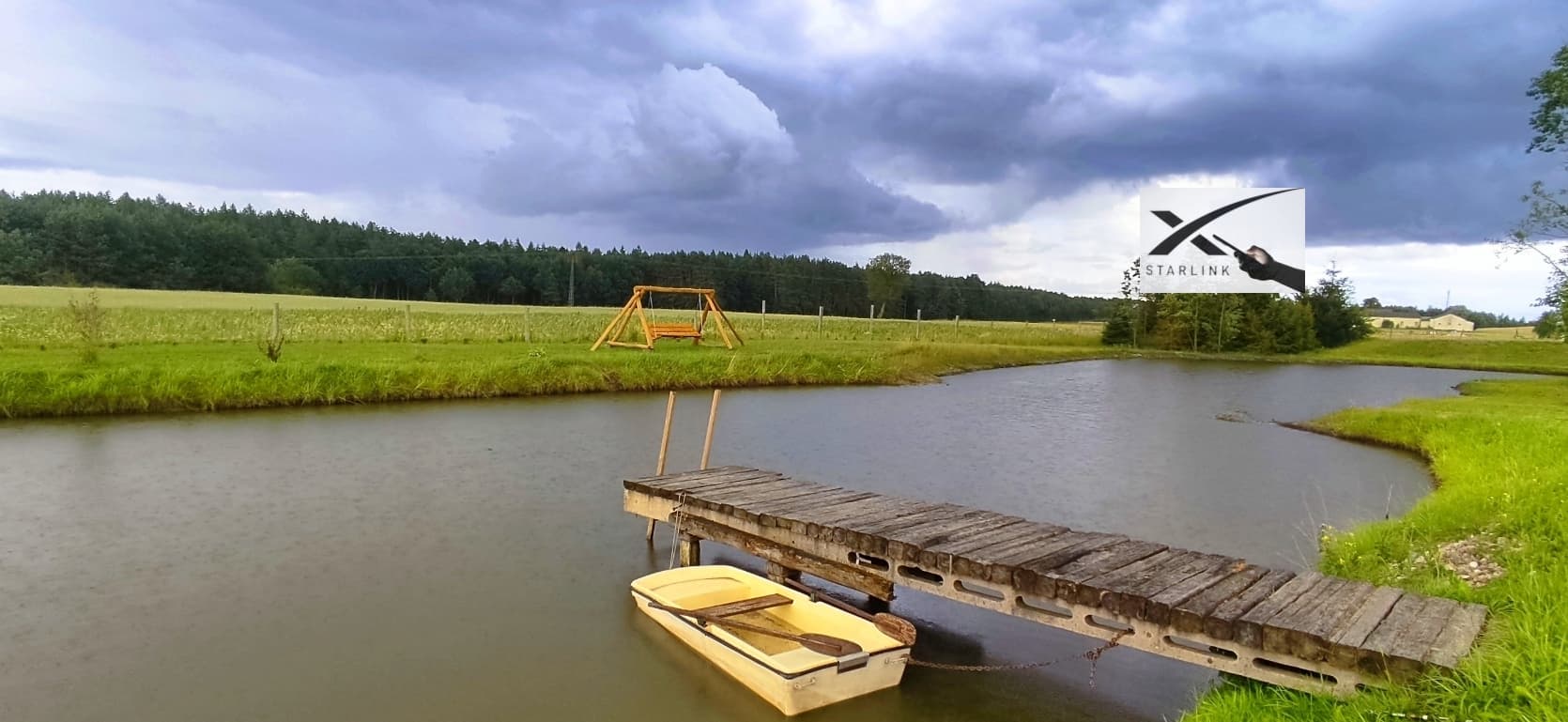 Staw z pomostem i łódkami obok domków